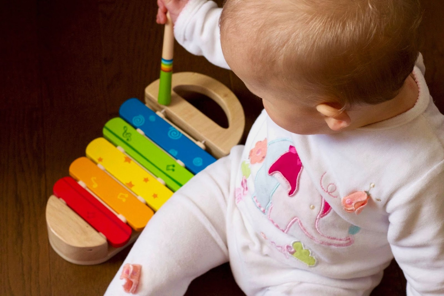 A baby playing with a toy in cotton rompers