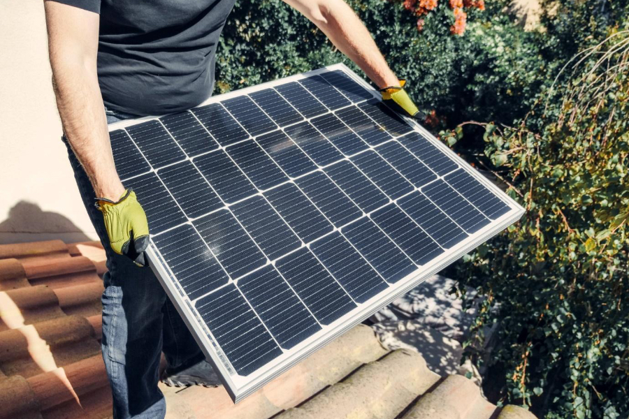 A man holding a solar panel for rooftop installation