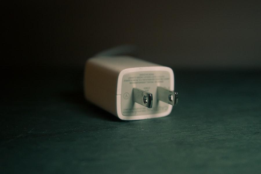 A single-region travel adapter on a grey desk