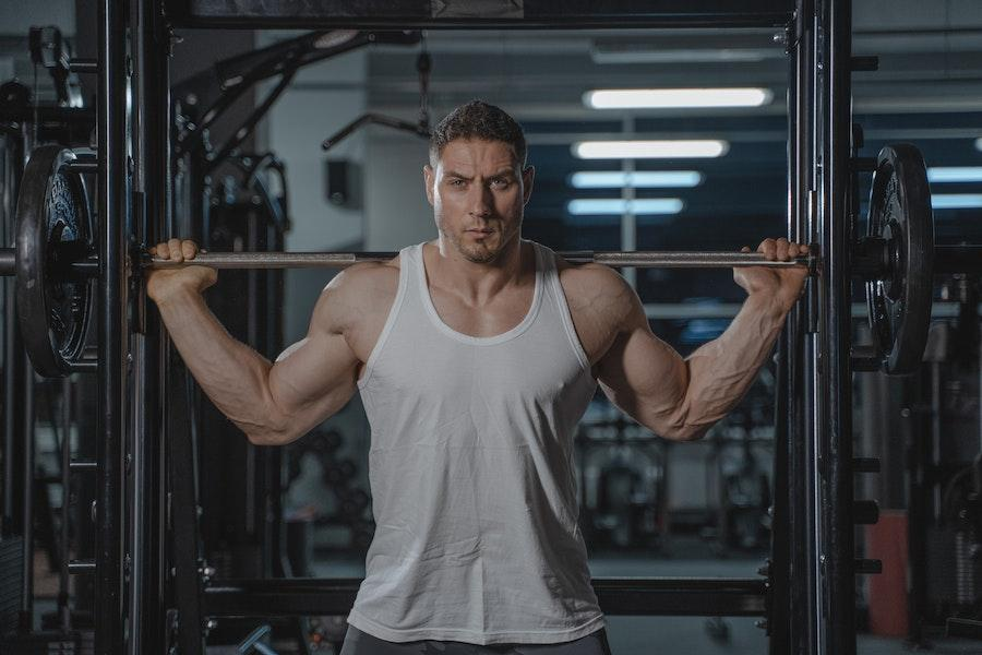 Hombre en el gimnasio con una camiseta sin mangas blanca