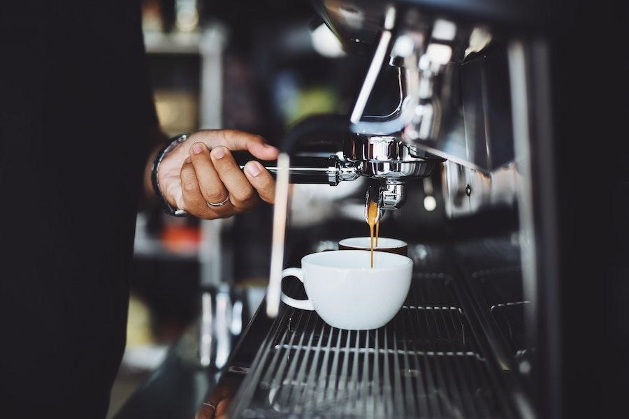 Man holding the handle of a coffee machine