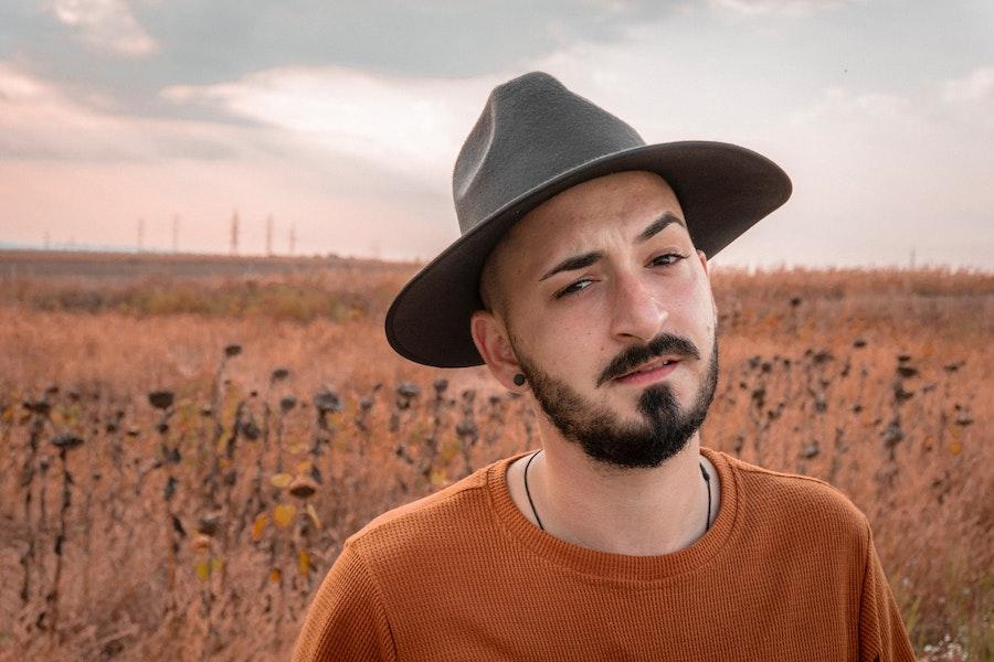 Homme dans un haut orange portant un chapeau de feutre