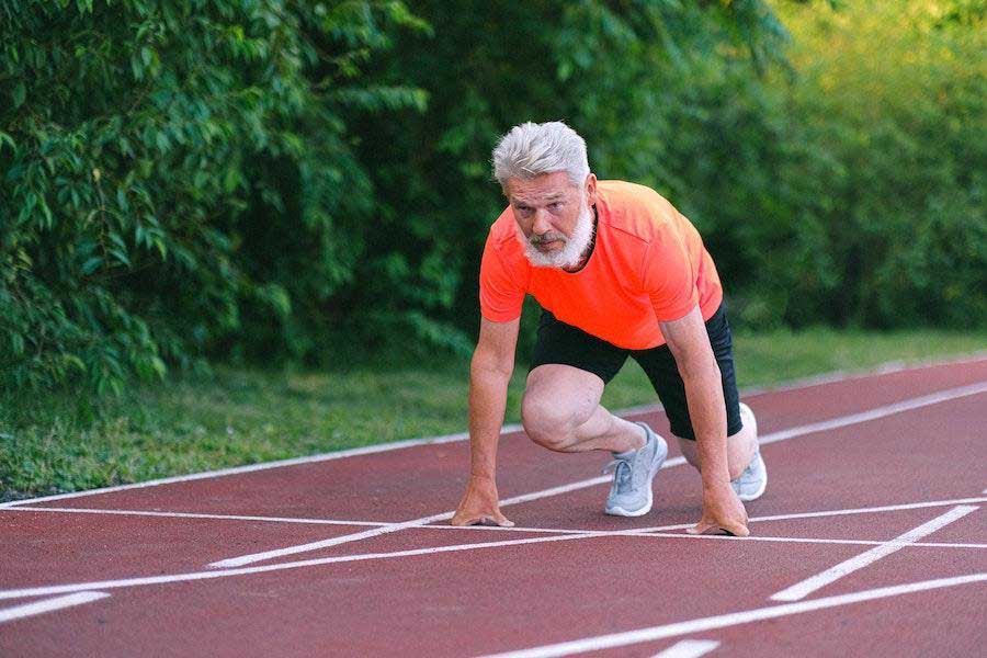 Mann in Laufposition trägt orangefarbenes Hemd und Shorts