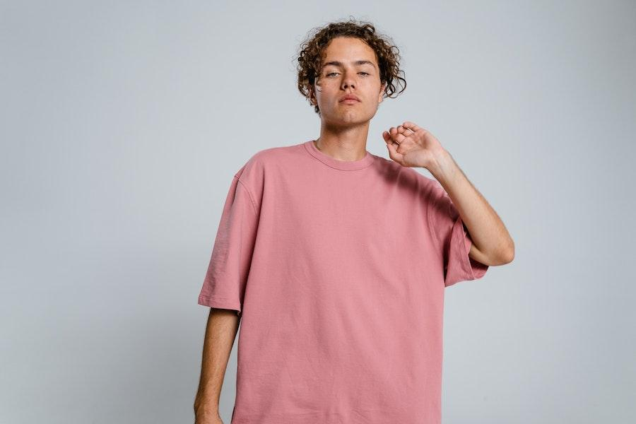 Hombre posando mientras mece una camiseta cuadrada rosa