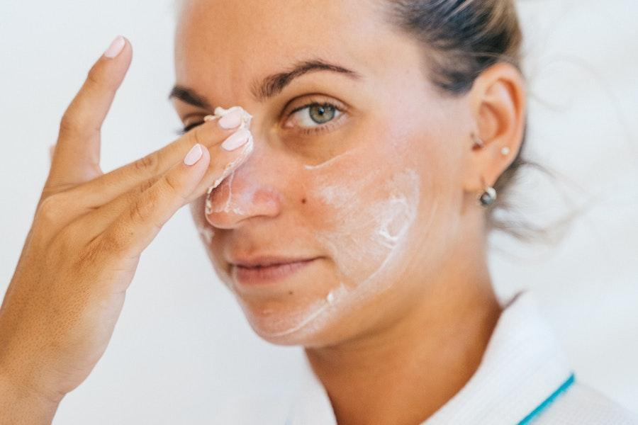 Woman applying facial cream on her face