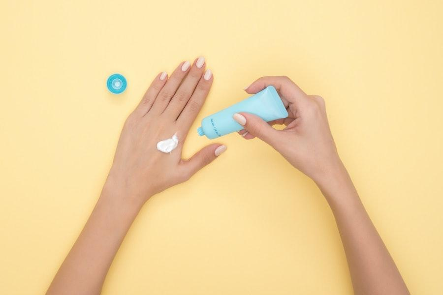 Woman applying hand cream from a blue reusable bottle