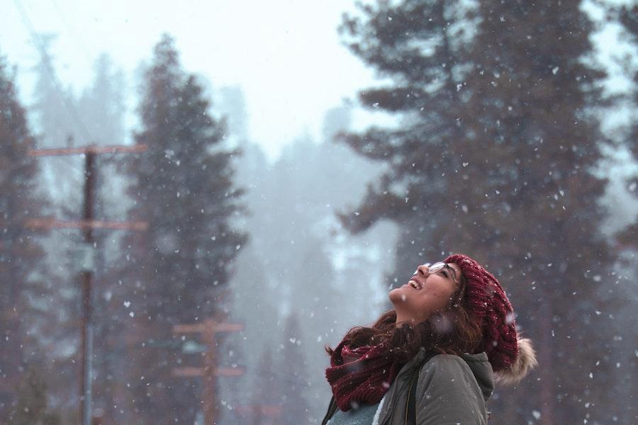 Woman looking up whale wearing a red pom-pom beanie