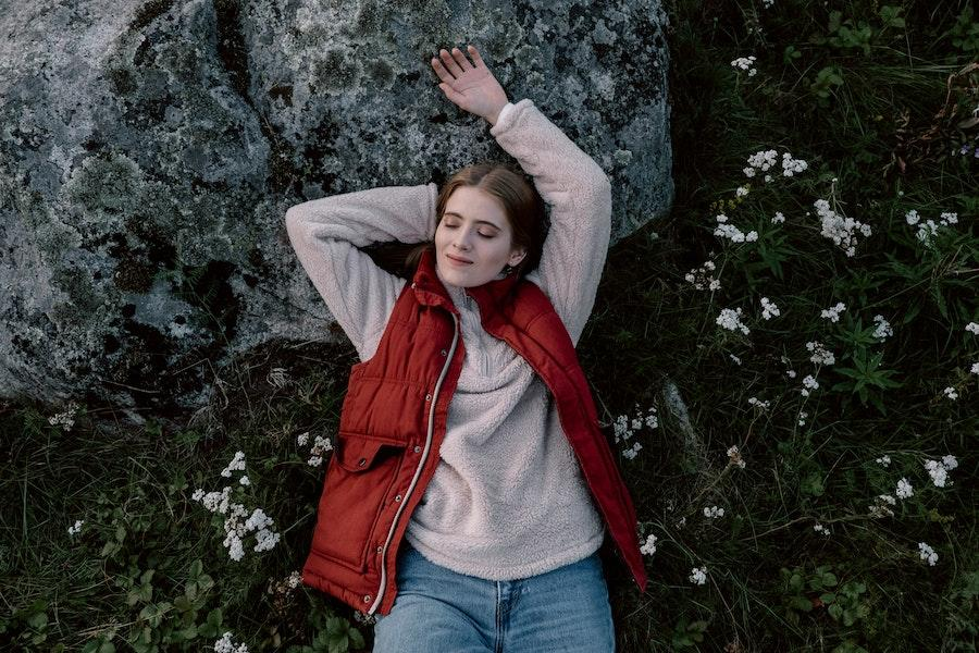 Woman rocking red utility vest while lying on a field