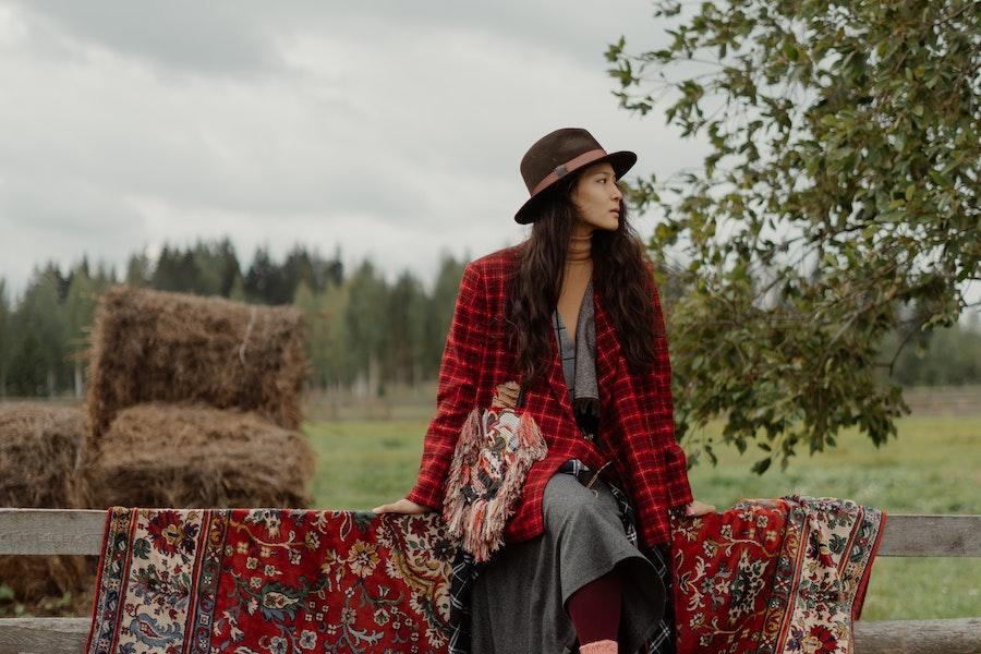 Woman sitting on a fence with a cowboy hat