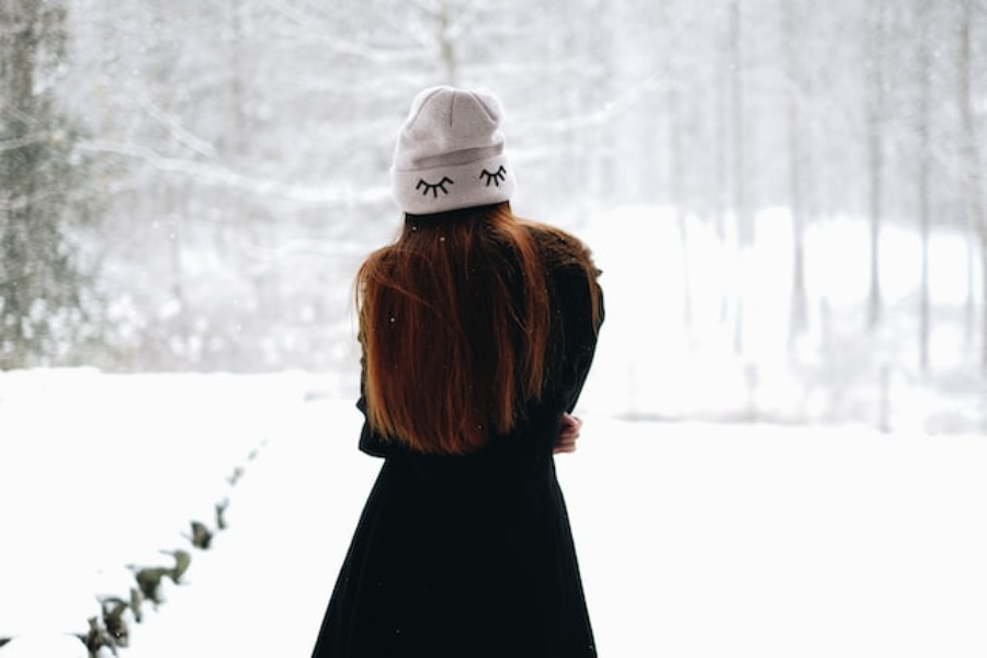 A woman wearing a white beanie hat embroidered with closed eyes