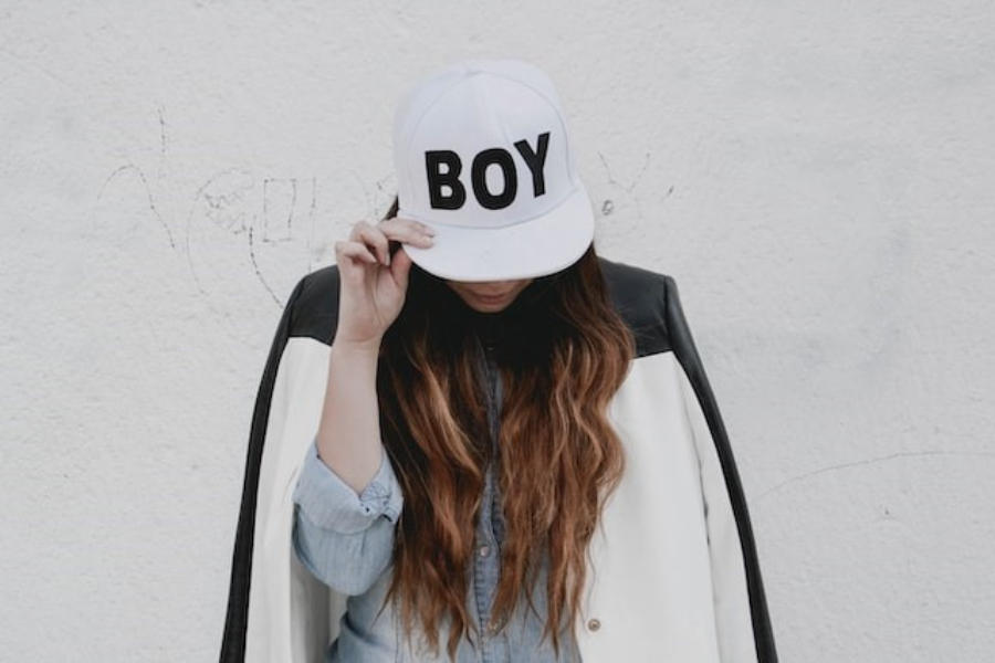 A woman wearing a white statement boy baseball hat